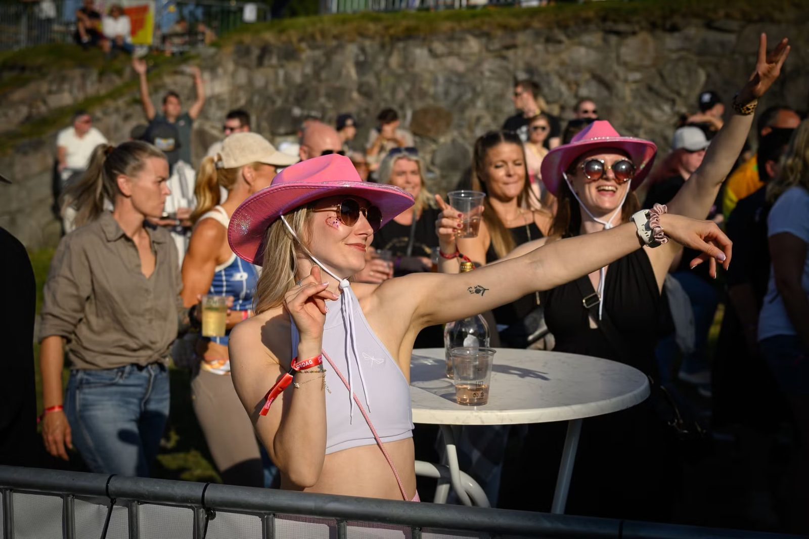 Festivalgjester med rosa cowboyhatter danser i solnedgangen